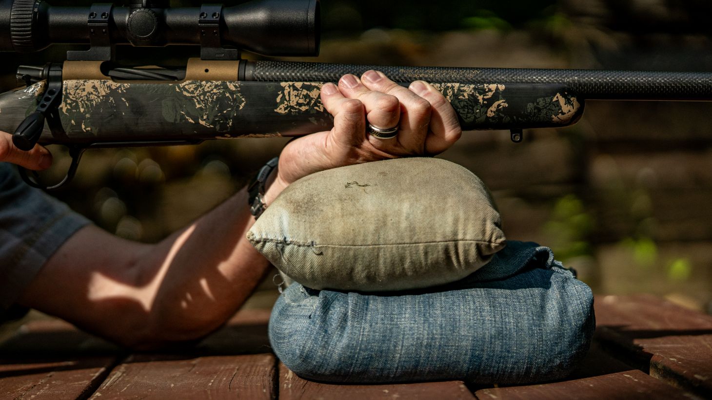 Closeup of a bench-rest shooter putting his hand under the forend of a hard-kicking rifle. 
