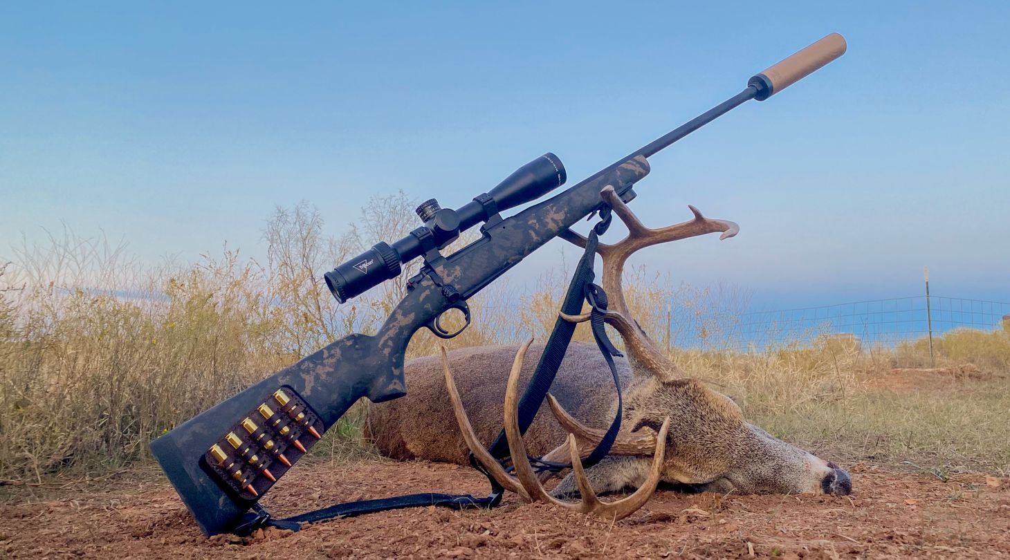 Gun with suppressor leaning on deer