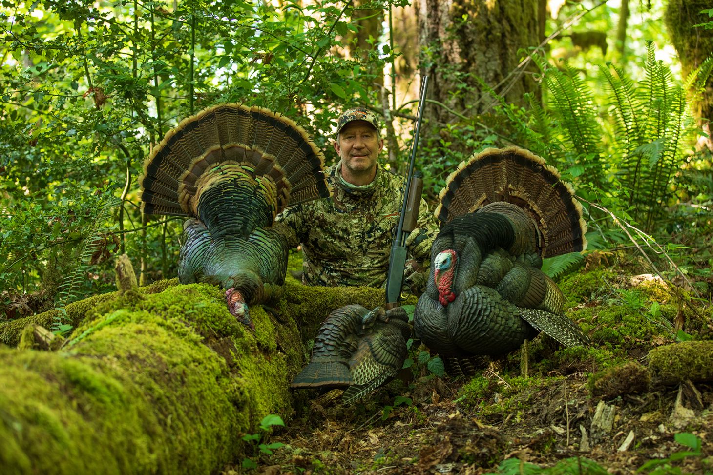 Hunter poses with turkey and decoy in the woods