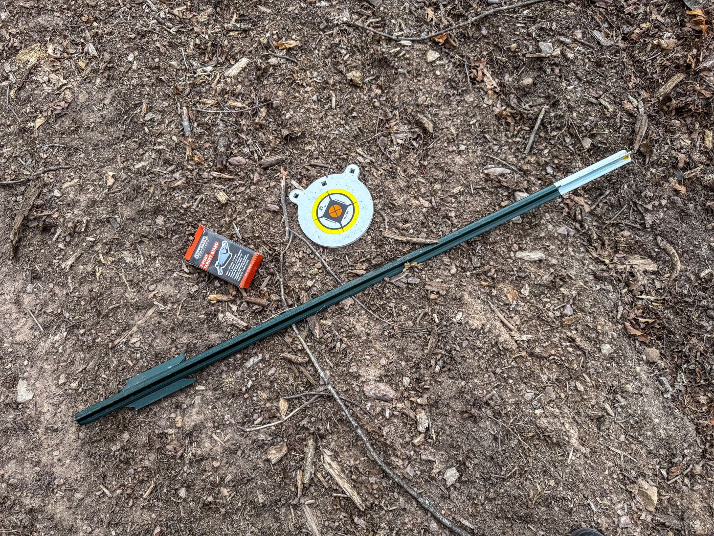 A steel target, hanger, and T-post ready for setup. 