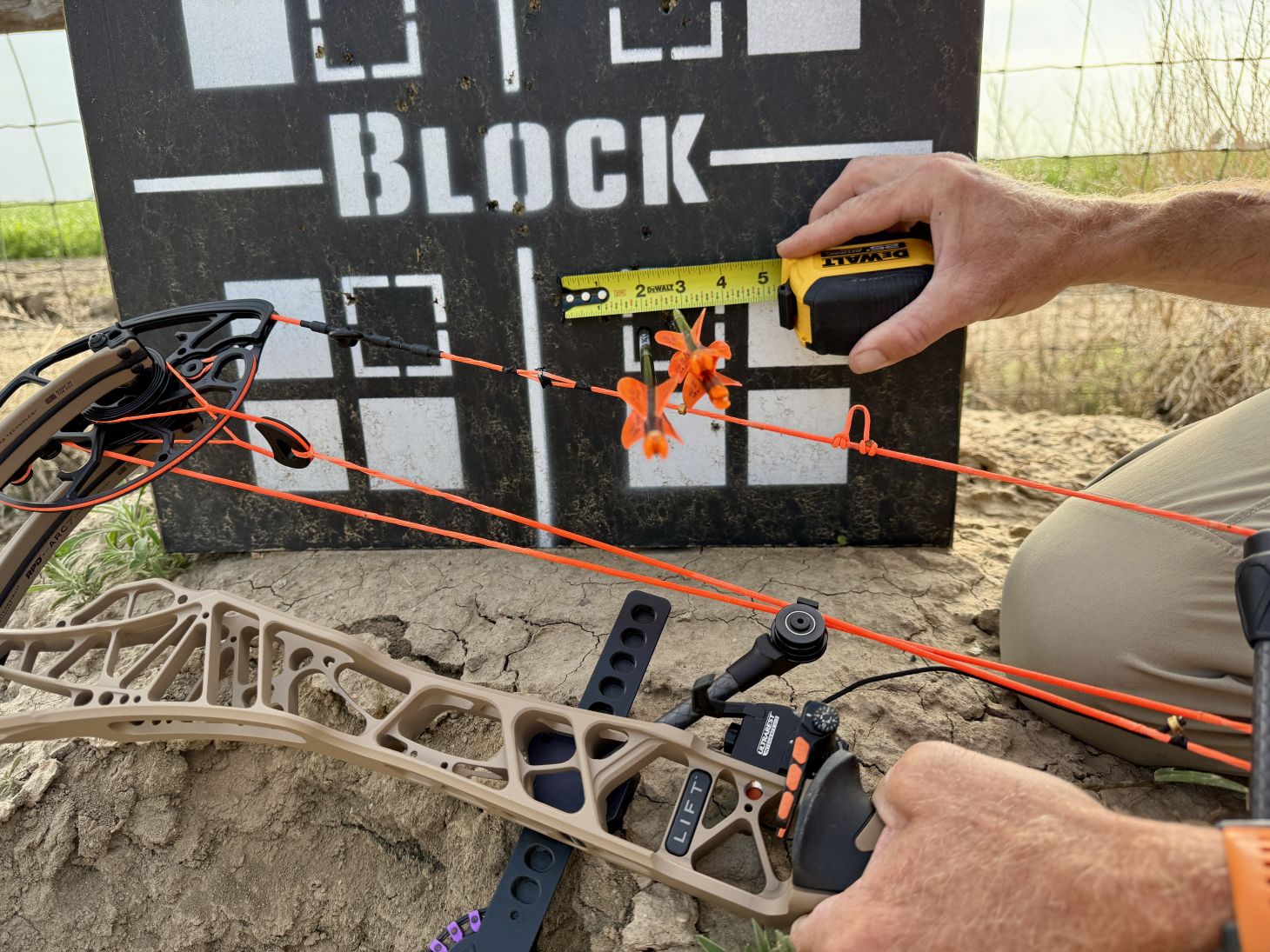 Photo of an archer measuring a group of arrow shot into a target. 