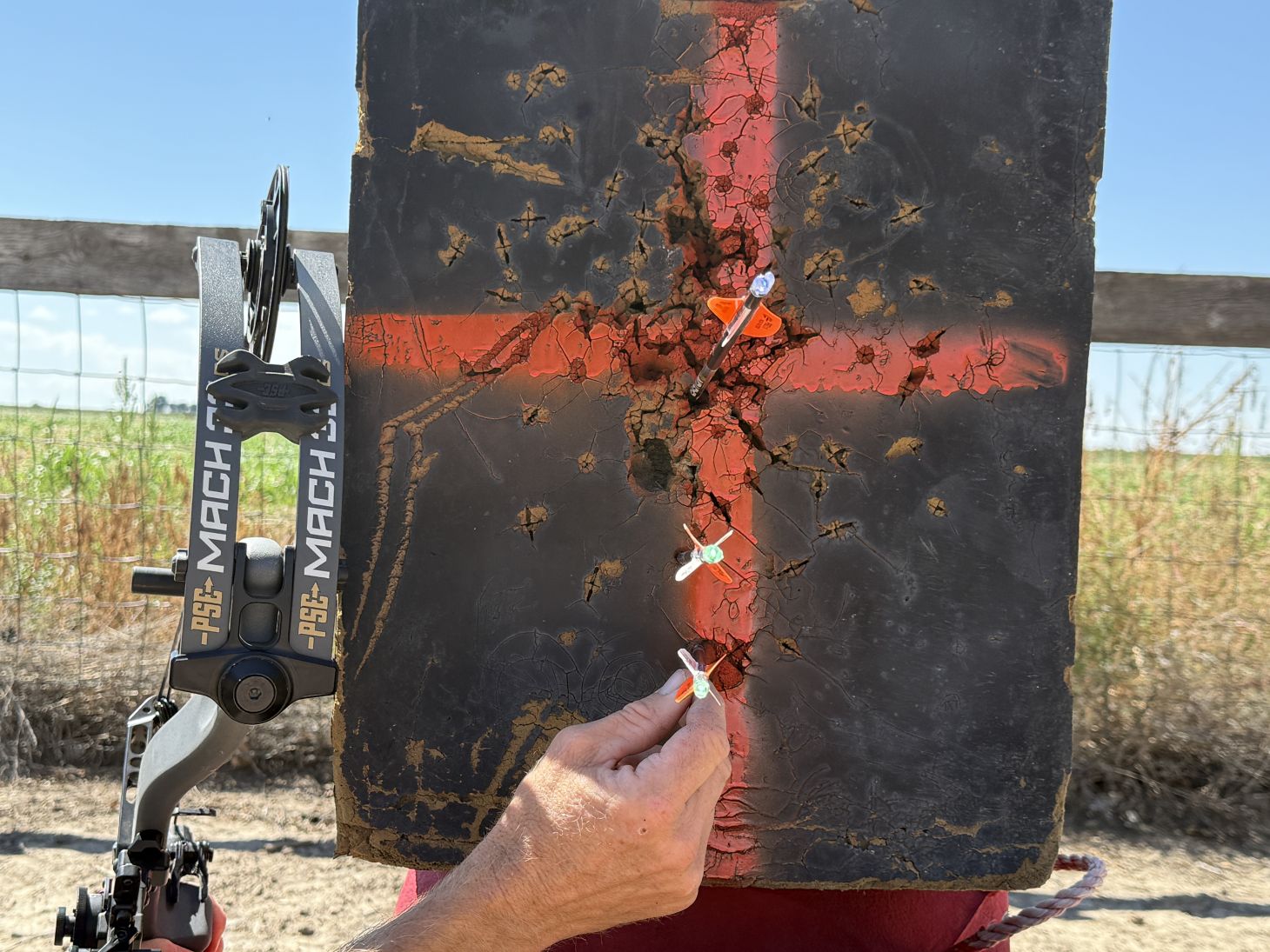 Three arrows lined up along a vertical axis on a bow target for walk back tuning. 