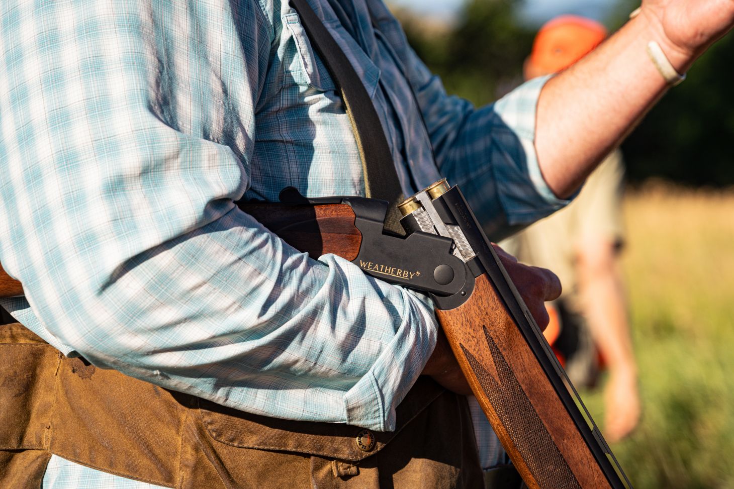 A hunter cradles an open Weatherby Orion over-under shotgun in his arm on a pheasant hunt. 