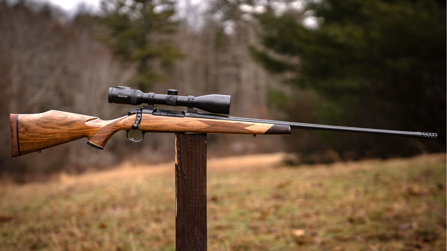 Weatherby Model 307 Adventure SD bolt-action rifle balanced on a post in a field.