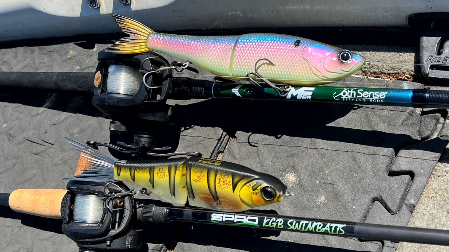 Two baitcasting rods on the deck of a boat rigged with glide baits