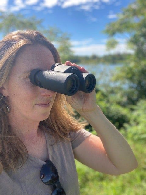 Female hiker looking through pair of binoculars
