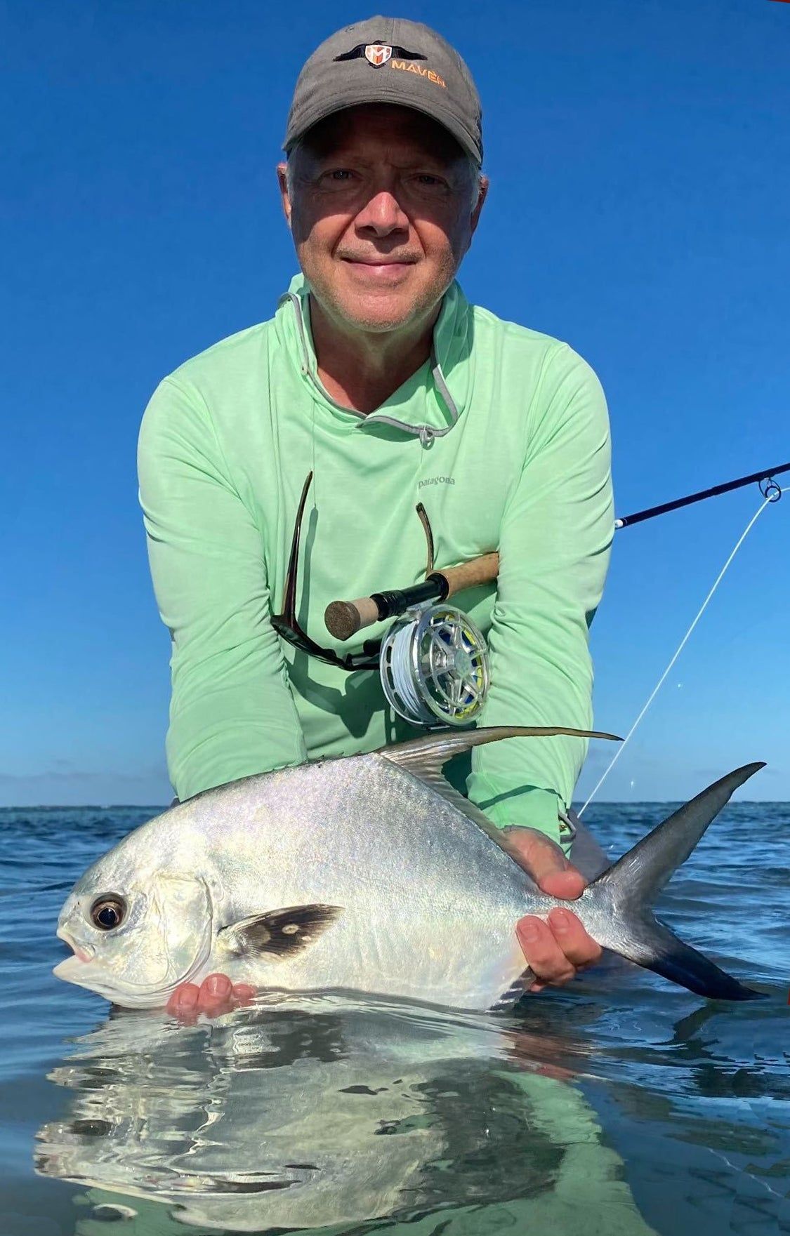 fly angler holds permit above water