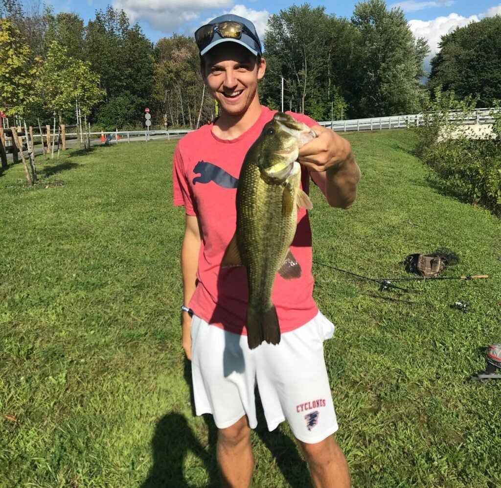 Fisherman holds a largemouth bass caught in a pond