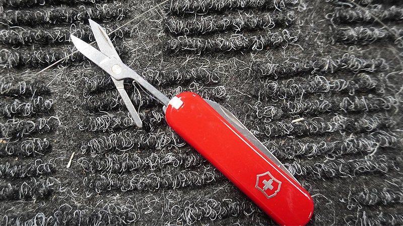 The scissors of the Swiss Army Classic SD on a black carpeted table top. 